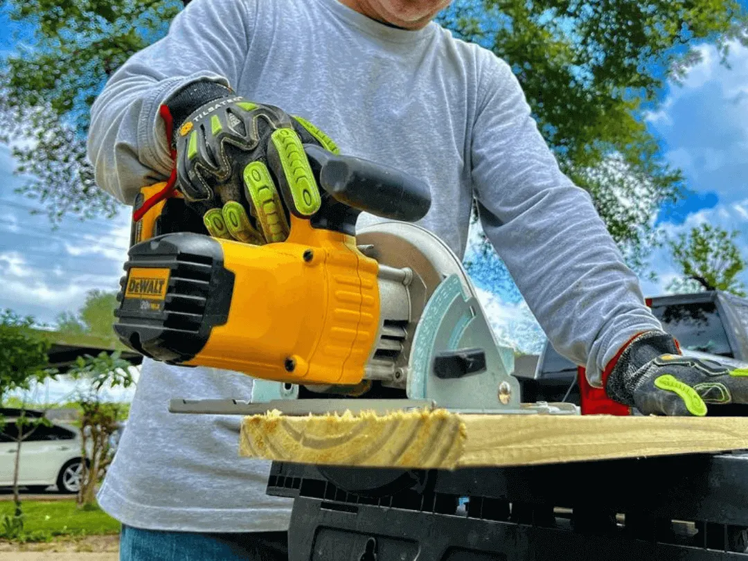 A skilled fence contractor wearing safety gear, expertly using an electric saw to precisely cut wooden planks for a custom fence installation.